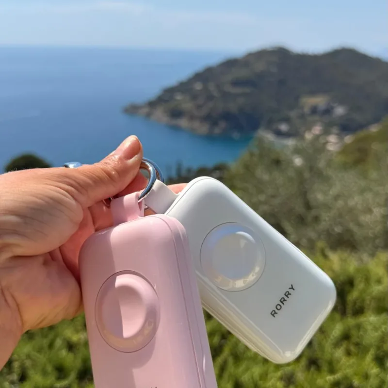 RORRY CharmGo D4 keychain power bank in Rose Quartz pink and Moonstone white, clipped to a bag